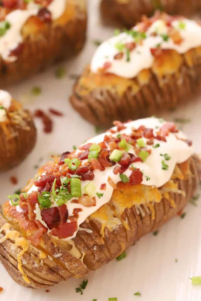 Fully loaded hasselback potatoes, topped with sour cream, bacon bits, sliced green onions, and plenty of cheese.