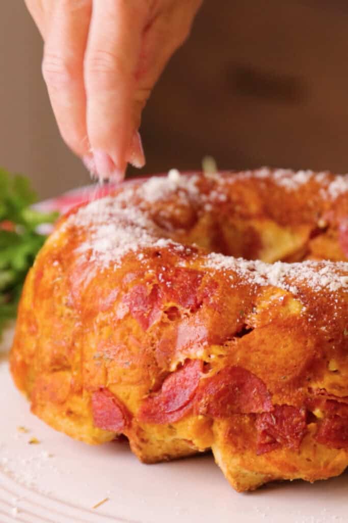 adding parmesan cheese to savory monkey bread