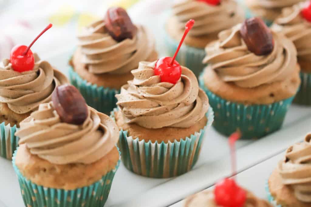 Delicious root beer cupcakes, topped with piped root beer frosting and maraschino cherries.