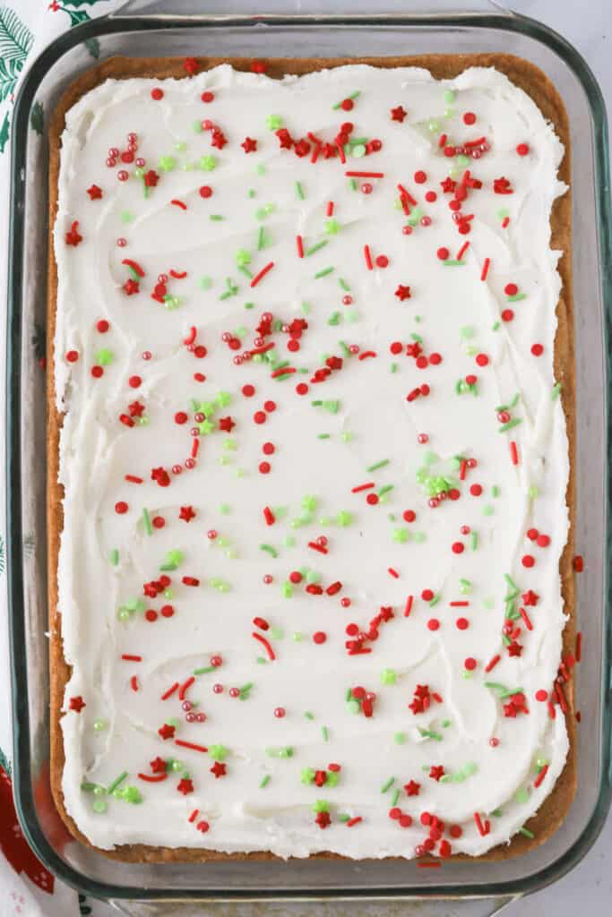 A baking dish full of Christmas bar cookies topped with buttercream frosting and holiday sprinkles. The best Christmas bar cookie recipe.