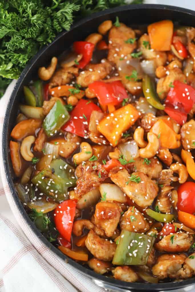 A large skillet full of cashew chicken with bell peppers and onions, the best recipe for cashew chicken you will ever try.