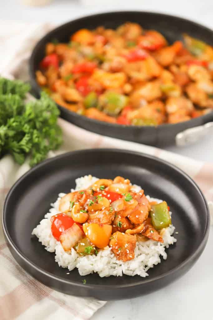 A plate with homemade cashew chicken over a bed of rice.