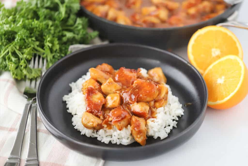 A plate with sticky orange chicken served over white rice. This is the best easy orange chicken recipe.