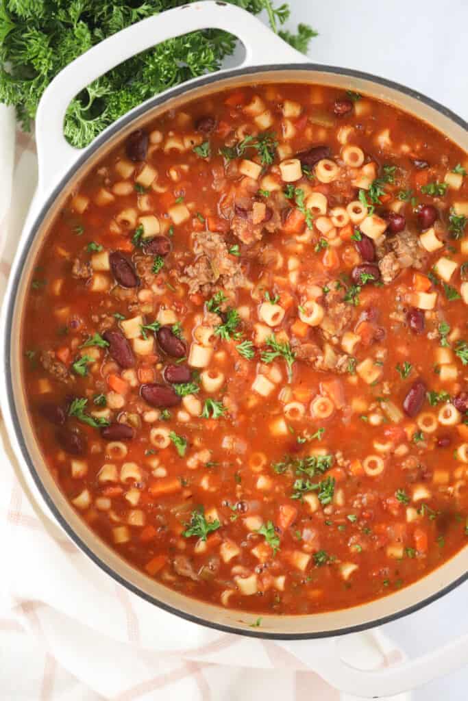 A large dutch oven full of pasta e fagioli soup, a hearty italian soup full of ground beef, veggies, pasta, and beans. This is a classic pasta fagioli soup recipe.
