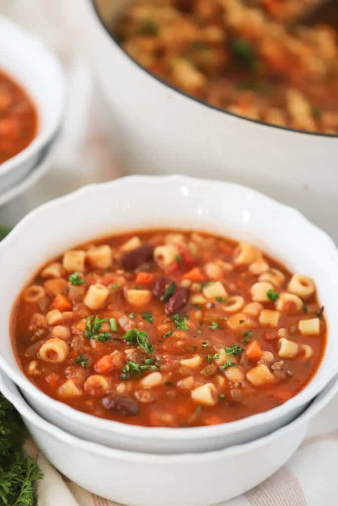 A serving bowl full of hearty pasta fagioli soup made with canned beans and ground beef.