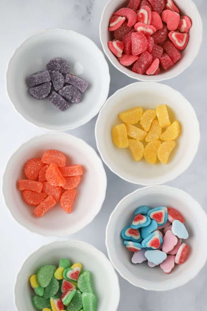 Individual bowls full of different colored gummy candies for making candy on a stick.