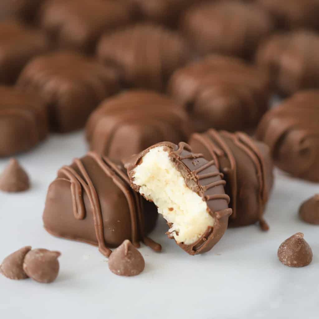 Coconut Mounds candy bars drizzled with chocolate. The coconut filling is made with sweetened condensed milk, shredded coconut, and a few other simple ingredients. Easy recipe coconut candy.