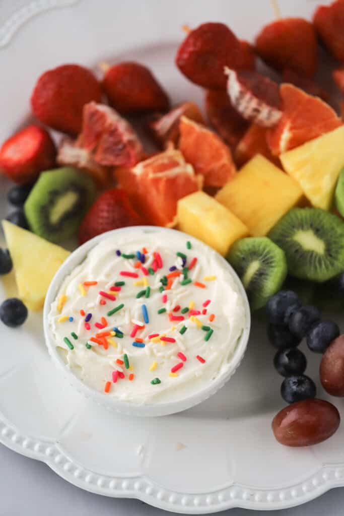 Quick and easy cream cheese fruit dip in a bowl surrounded by fresh fruit.