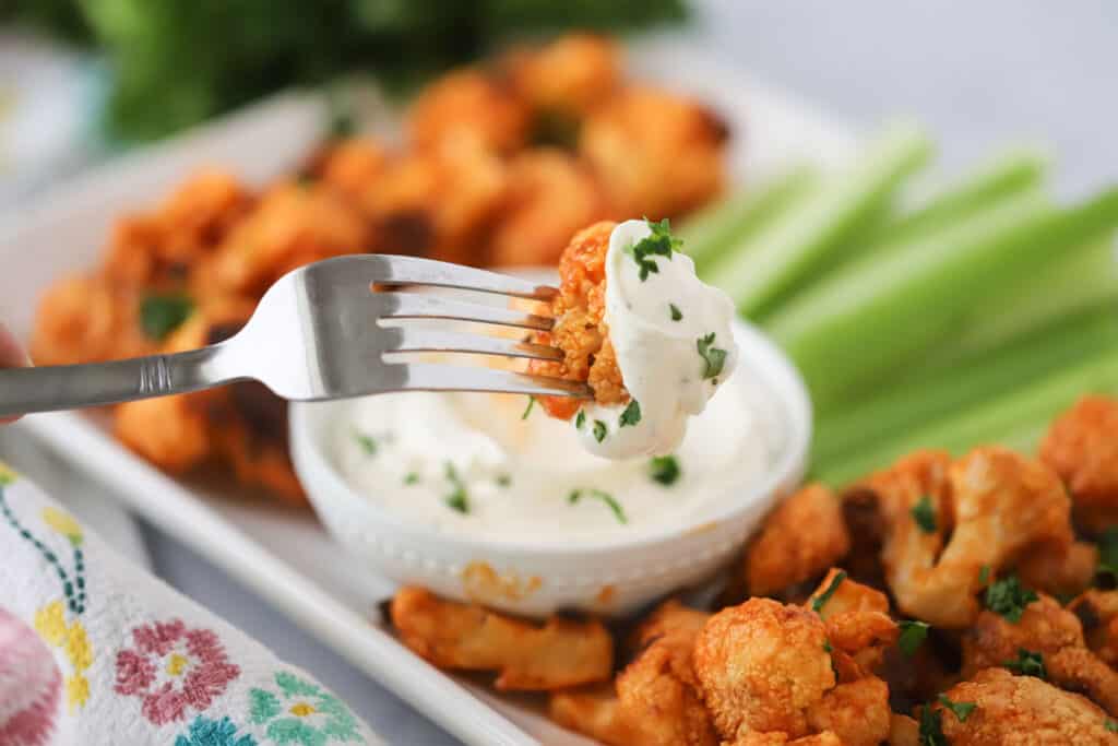 Hidden Valley Ranch dip recipe, in a small bowl served with buffalo cauliflower and celery sticks.