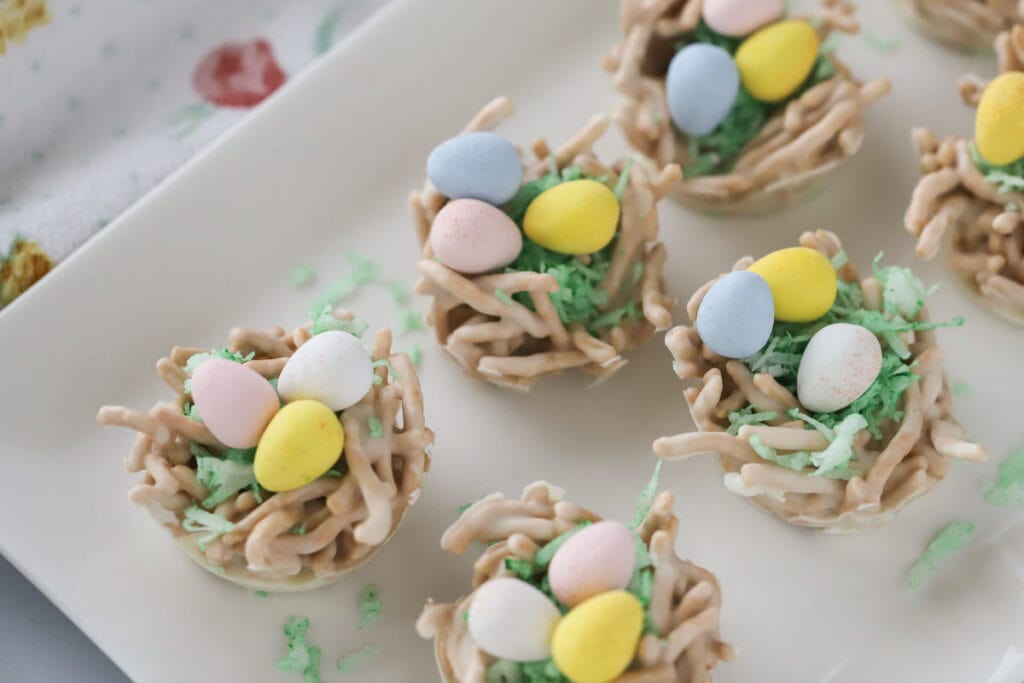 Chow mein noodle haystacks turned into easter dessert by using coconut grass and mini candy eggs.