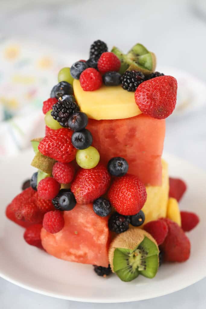 A Fresh Fruit Cake made with watermelon, pineapple, berries, kiwi, and mango on a serving plate.
