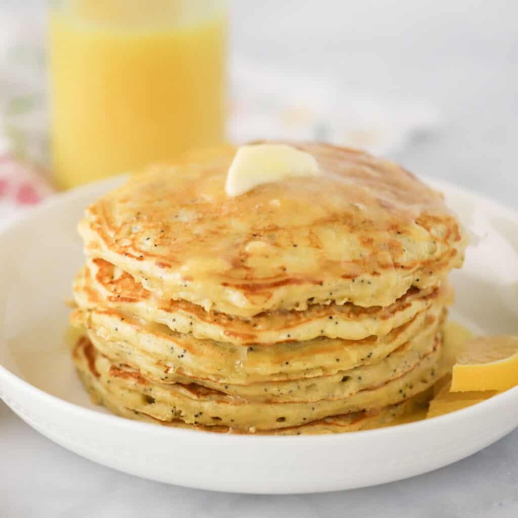 A stack of lemon poppy seed pancakes with butter, an easy lemon poppy seed pancake recipe.