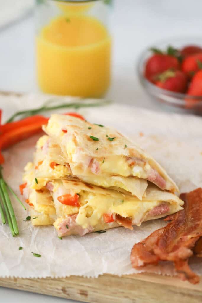 A stack of Breakfast quesadillas filled with scrambled eggs, red pepper, bacon, and ham.