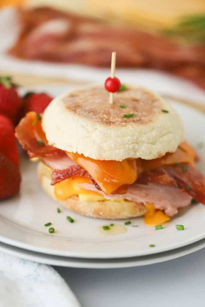 A homemade Egg McMuffin on a plate with a large pick in the center.