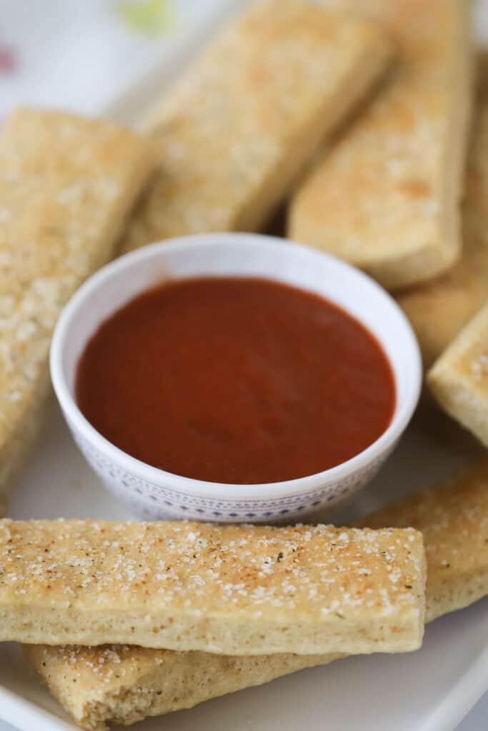 Whole wheat breadsticks with a side of marinara sauce.
