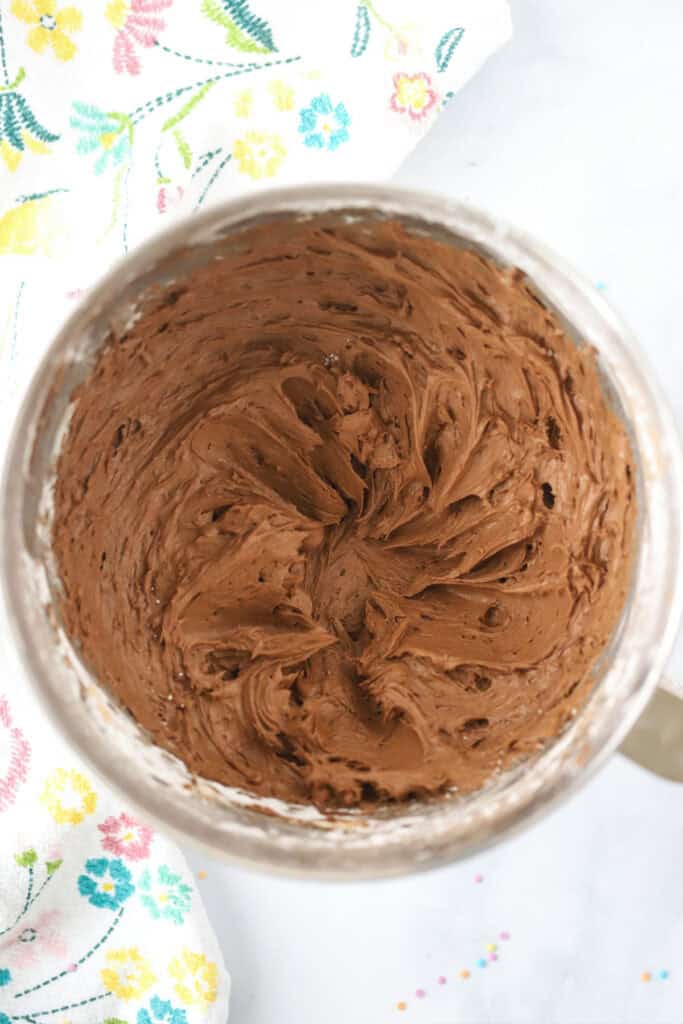 A bowl full of chocolate cream cheese frosting on a tabletop.