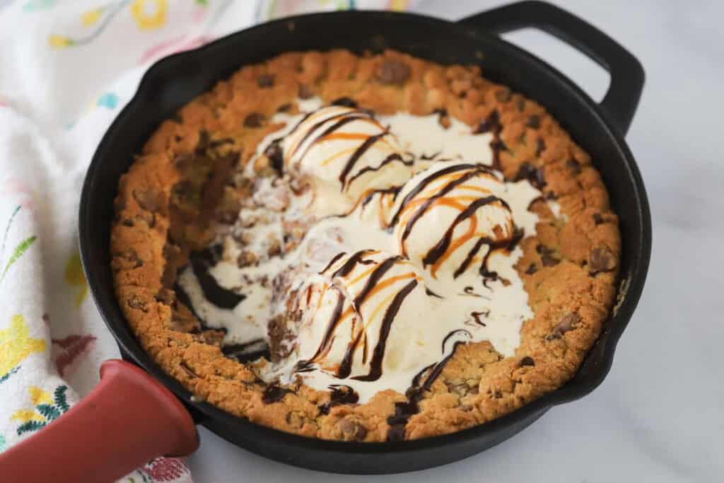A skillet with a pizookie skillet cookie baked into the center and topped with vanilla ice cream.