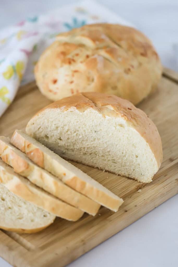 A cutting board with Rosemary Parmesan Bread being sliced.