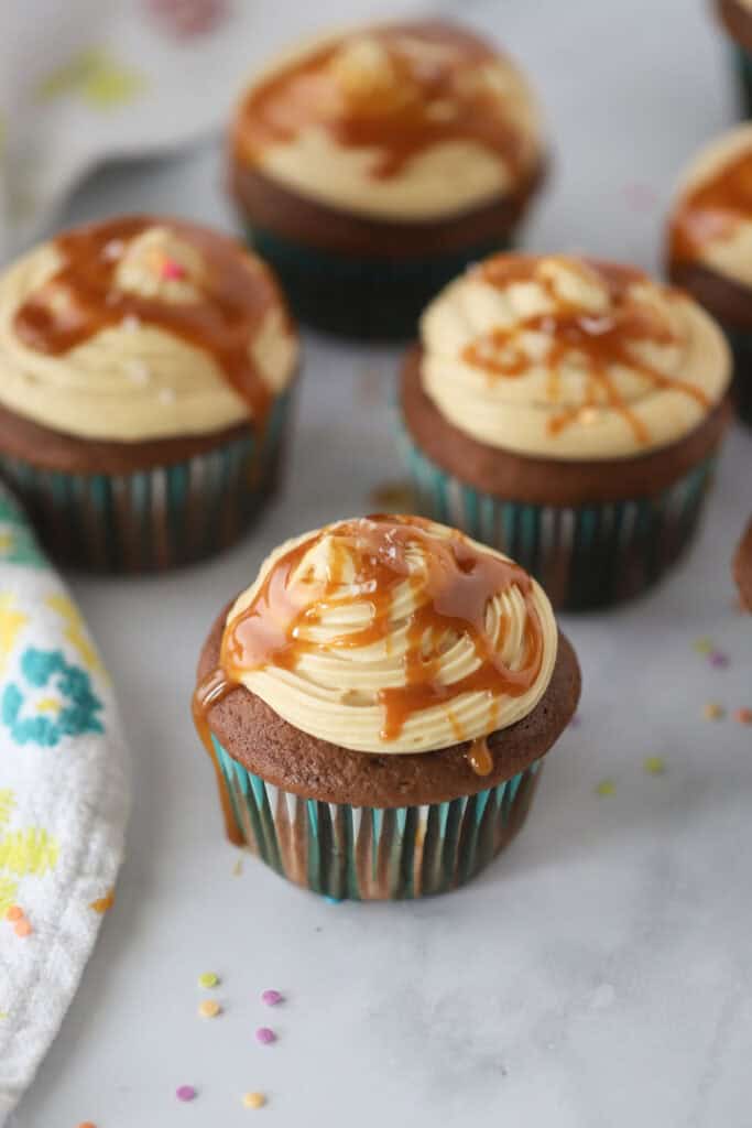 Chocolate cupcakes topped with salted caramel frosting and a drizzle of caramel sauce.