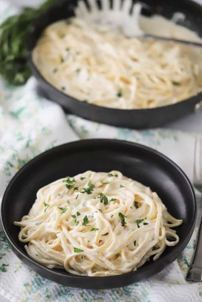 A bowl full of fettuccine alfredo with asiago sauce.