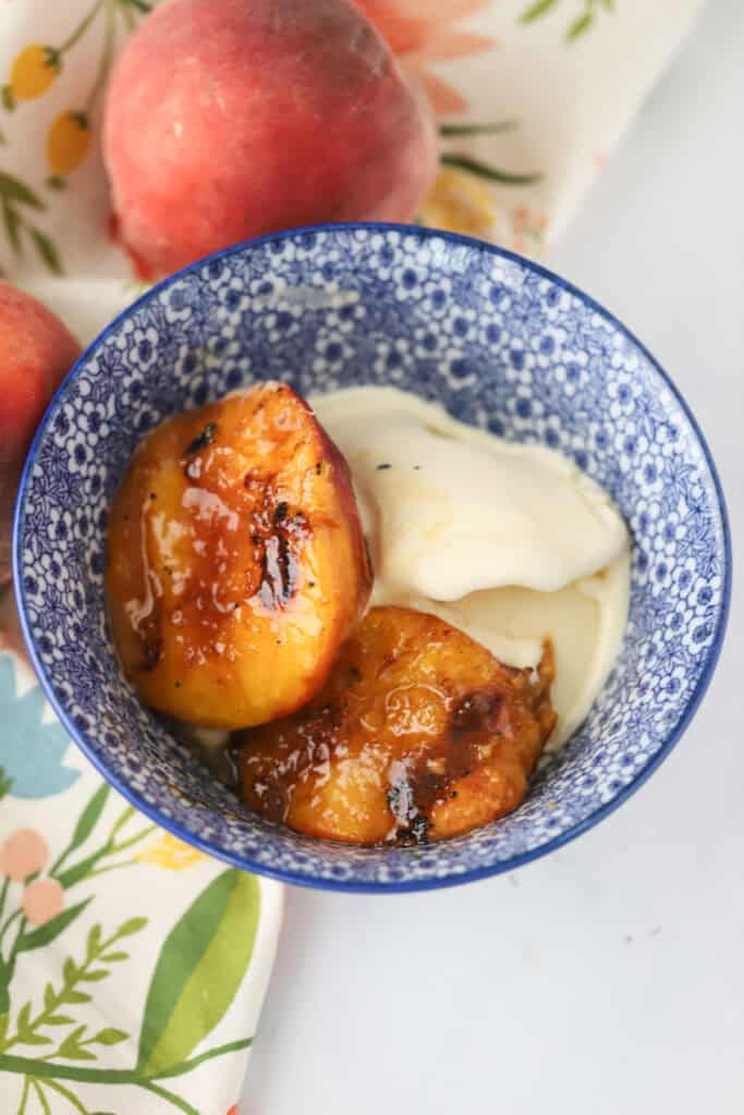 A bowl with grilled peaches and vanilla ice cream.