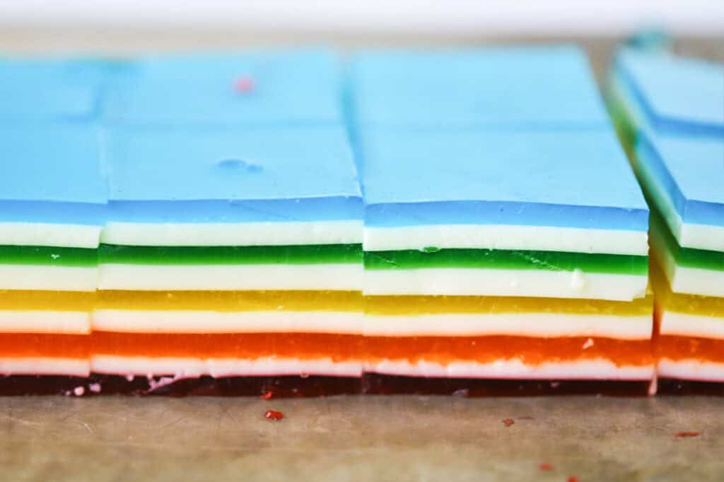 Cut squares of rainbow layered jello.