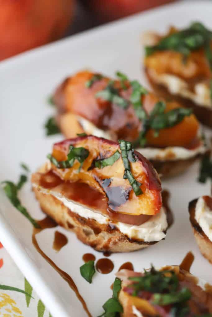 Grilled Peach Crostini made with honey cream cheese and topped with balsamic glaze and fresh basil.