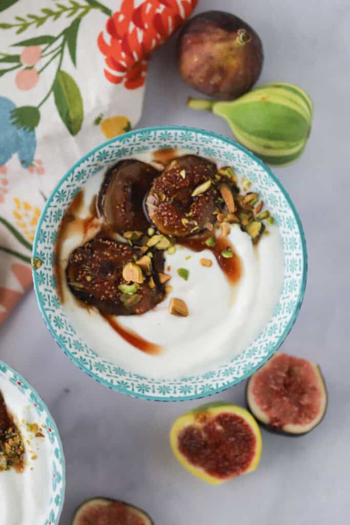 A small bowl of Greek yogurt with figs, honey, and pistachios.