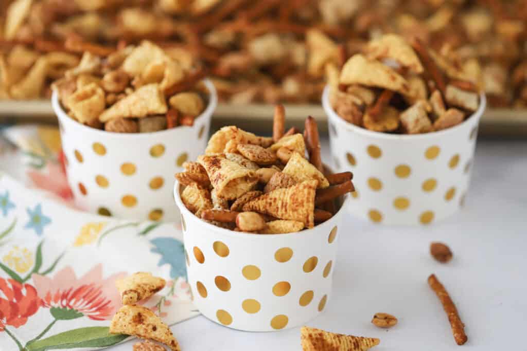 Small cups full of homemade Chex Mix made with Bugles, pretzels, and peanuts.