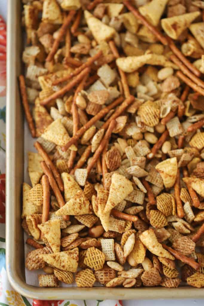 A sheet pan with an even layer of Chex Party Mix ready to toast in the oven.