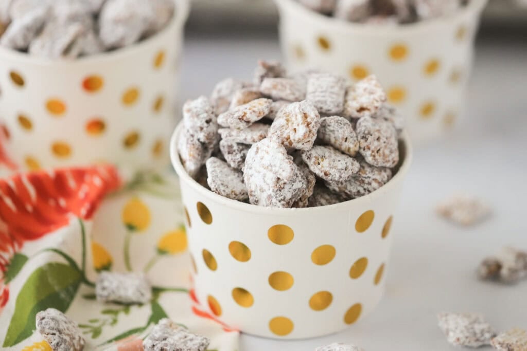 A small individual cup with gold dots filled with muddy buddies.