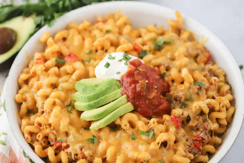 A big bowl of cheesy taco pasta with taco toppings.