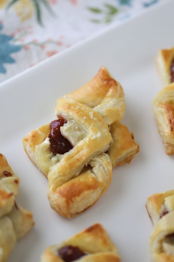 A serving platter with fig and brie puff pastry bites.