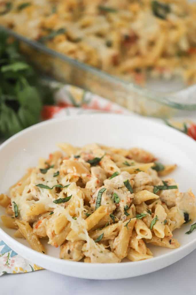 A serving bowl full of Marry Me Chicken Pasta bake topped with fresh basil.