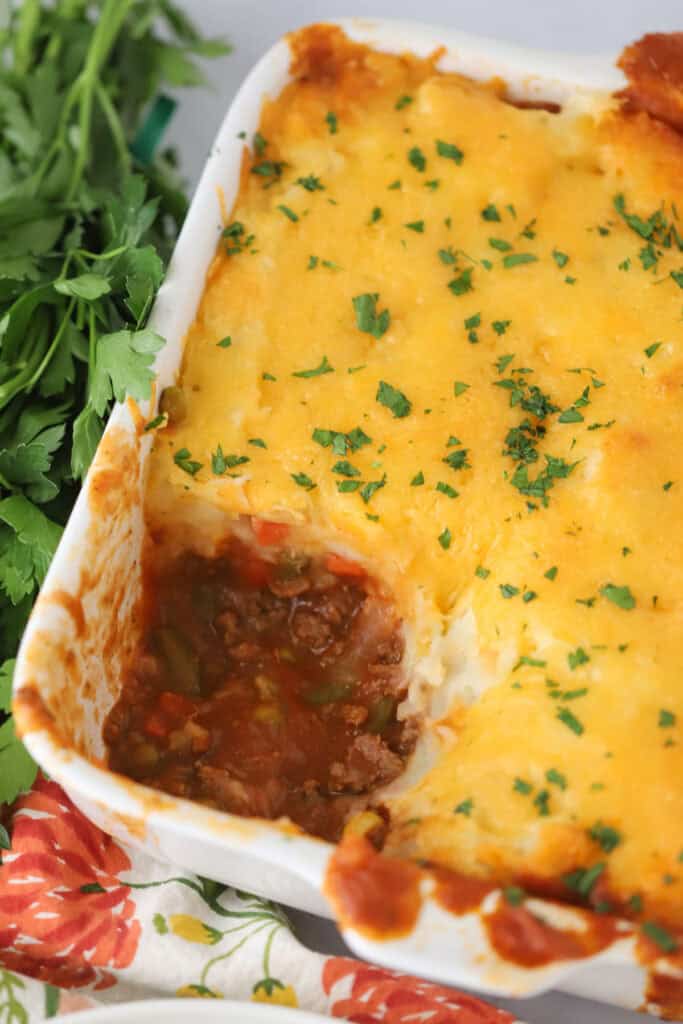 A large baking dish full of shepherd's pie with a large portion removed.