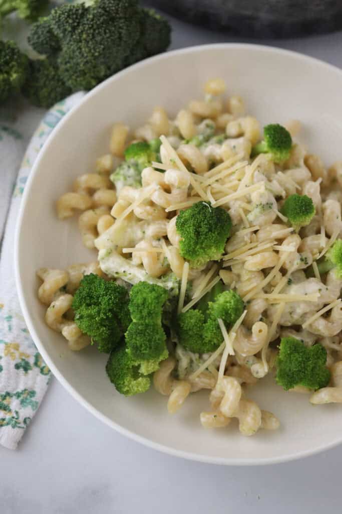 A white serving bowl full of this creamy broccoli pasta recipe, topped with shredded Parmesan cheese.