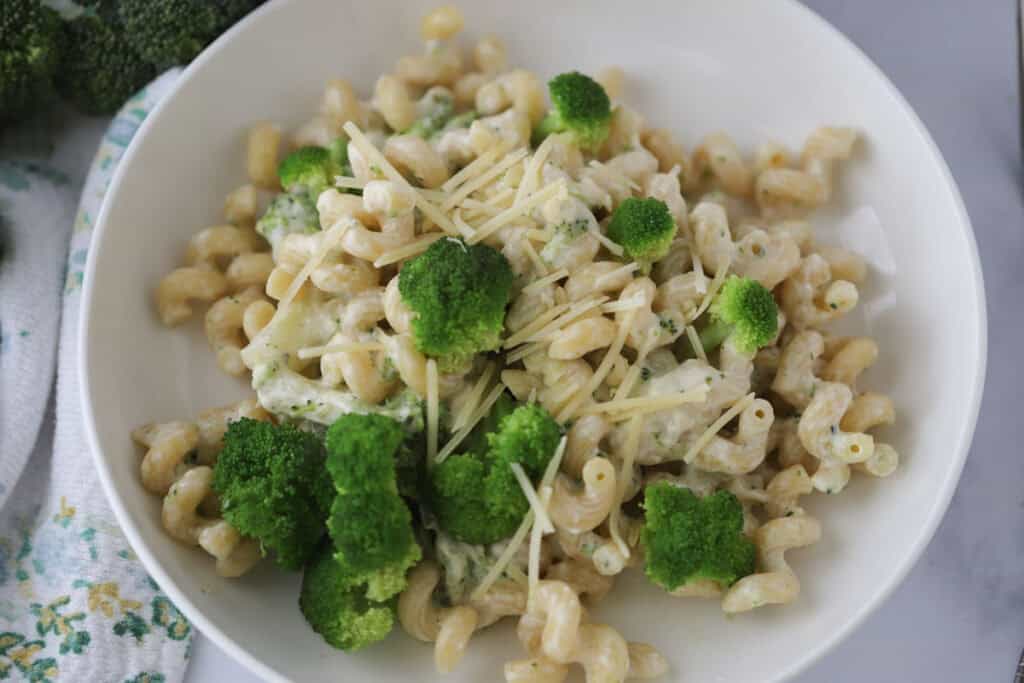 Cavatappi pasta in a white bowl with creamy sauce and broccoli.