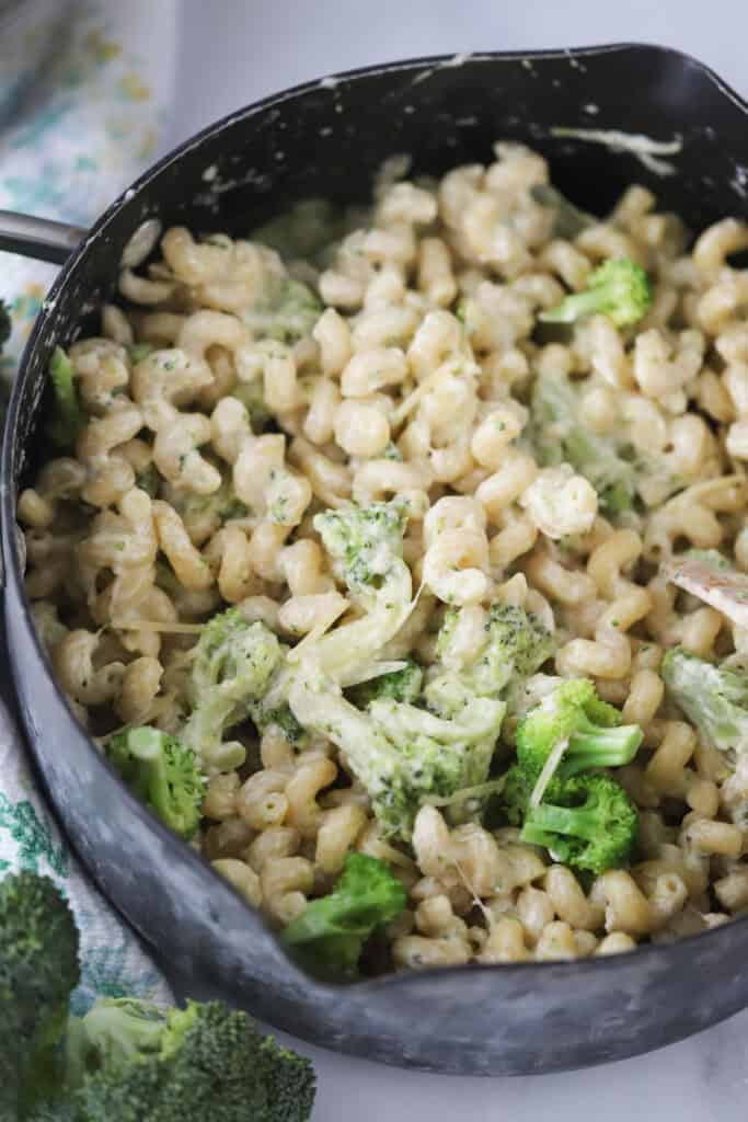 A saute pan full of pasta and broccoli with a creamy sauce.