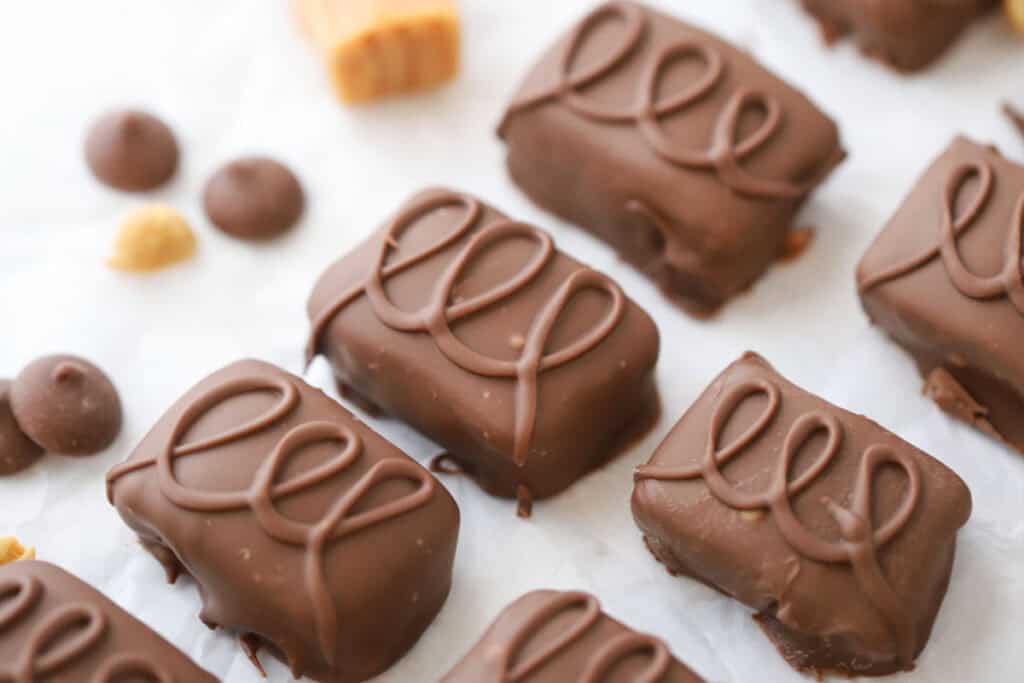 Homemade snickers candy bars on a baking sheet covered with parchment paper.