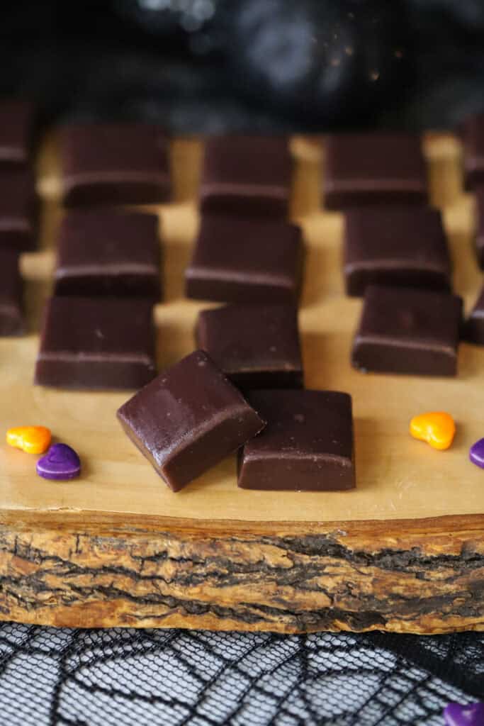 A serving platter full of squares of black licorice caramels.