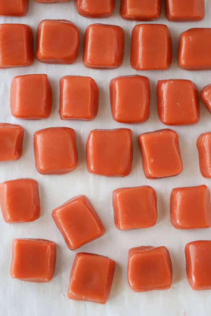 A baking sheet with squares of homemade caramel candy ready to wrap.