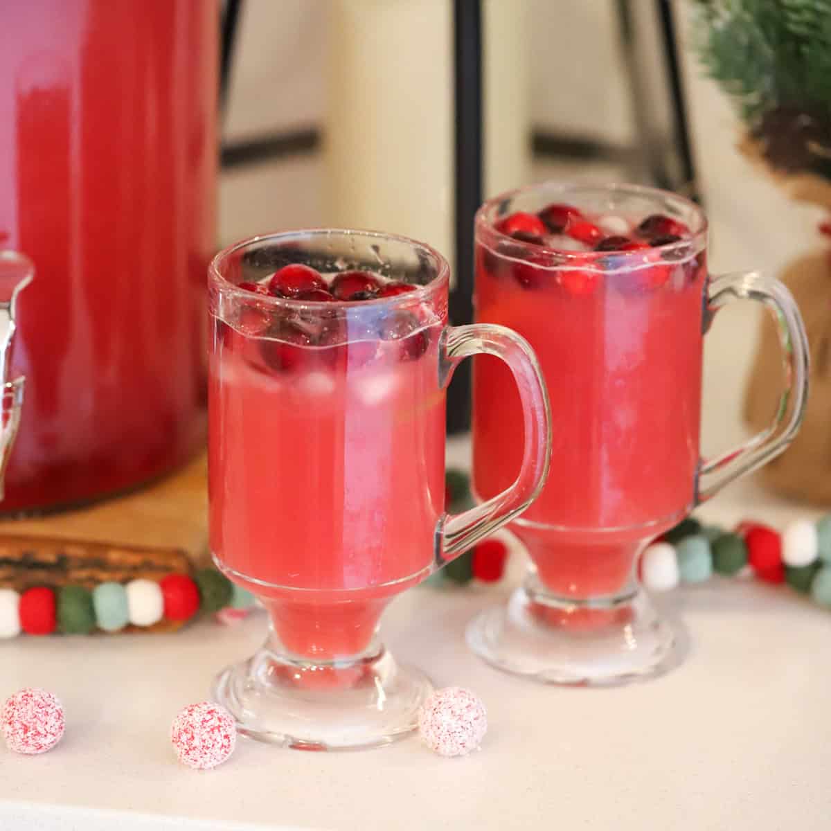 Two glasses full of Christmas punch, garnished with fresh cranberries.