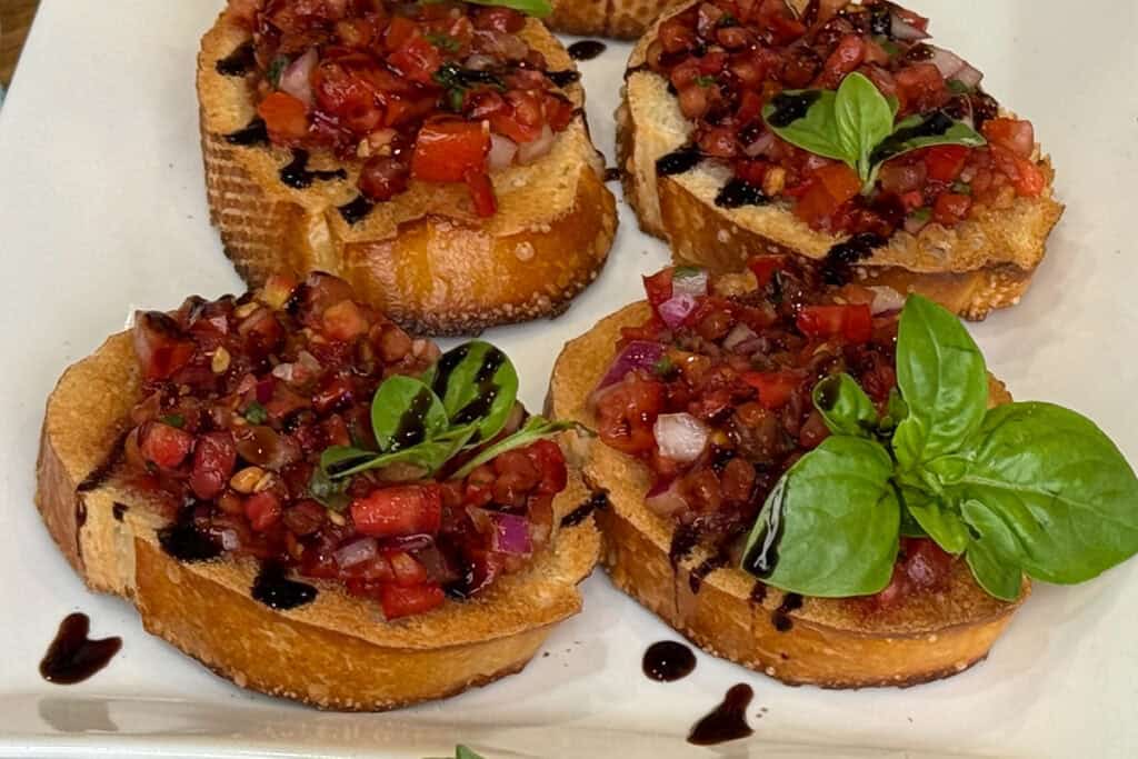 Tomato bruschetta topped with fresh basil on a sheet tray
