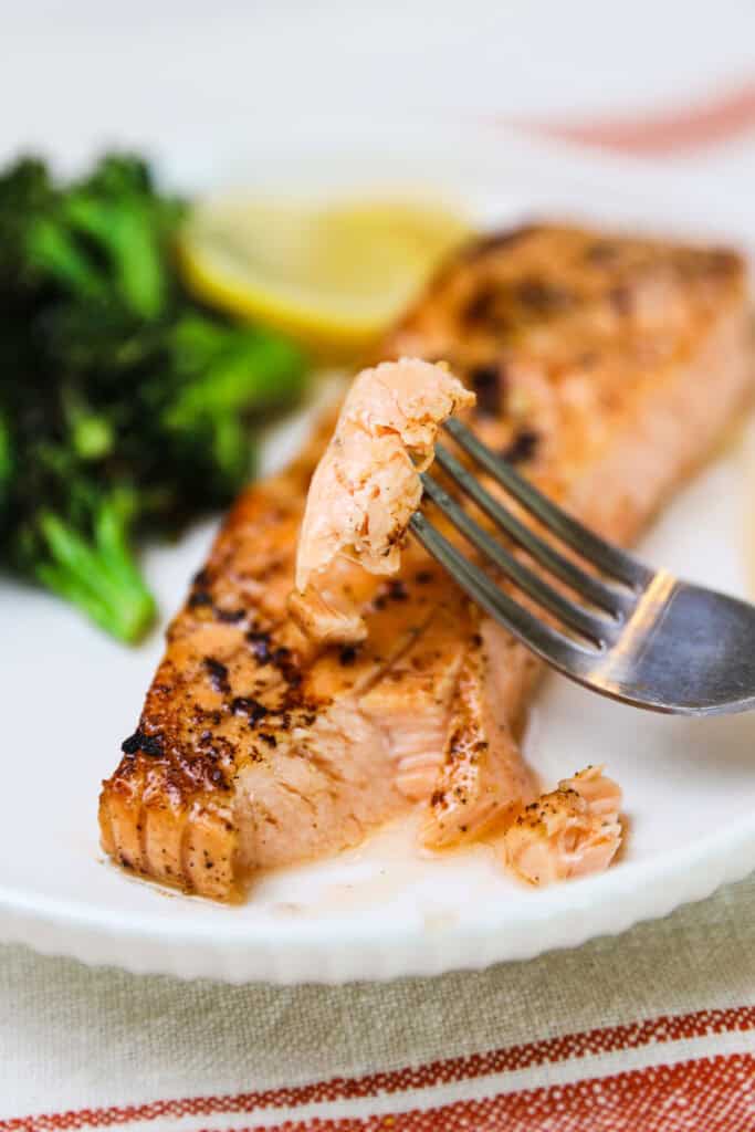 A plate with baked garlic lemon salmon and a side of broccoli.
