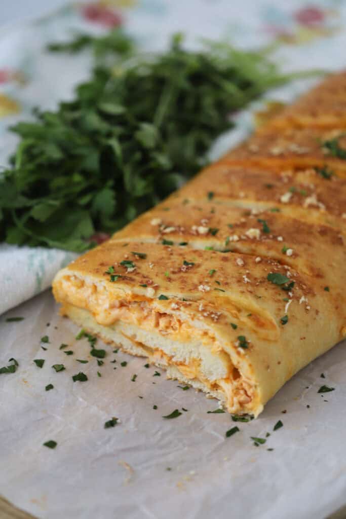 A baking sheet with buffalo chicken stromboli missing a slice.