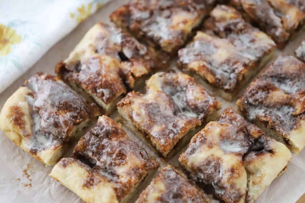 Cinnamon focaccia cut into pieces on a cutting board.