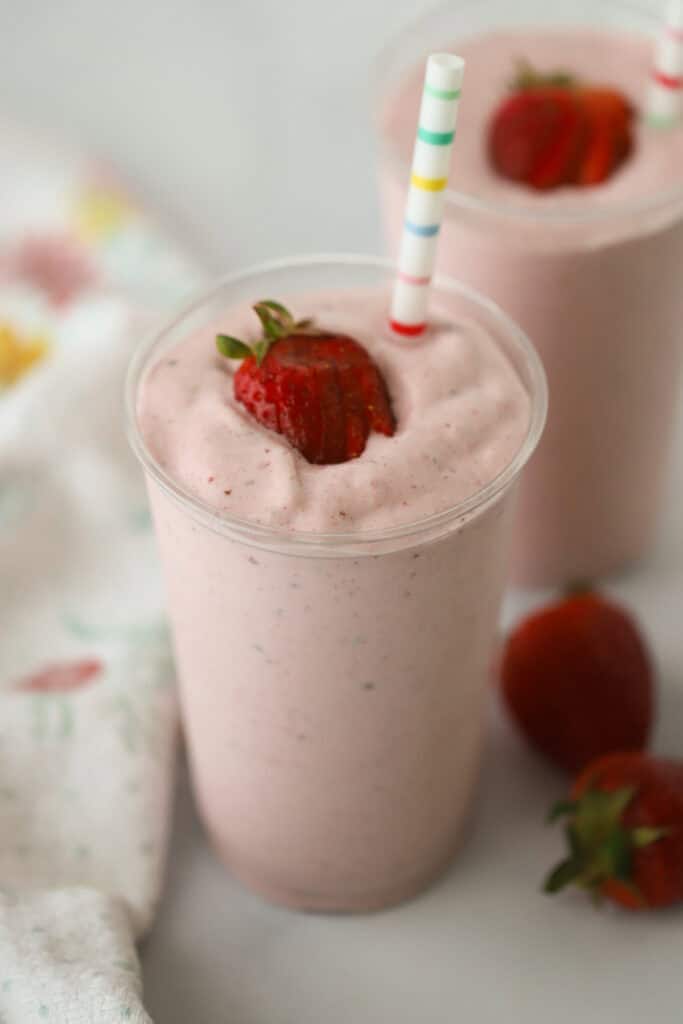 Strawberry Protein Smoothie with a decorative straw and garnished with a strawberry.