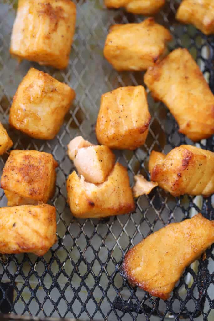 An air fryer basket with salmon bites.
