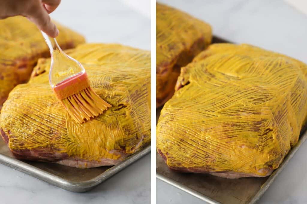 Brushing mustard over pork shoulder.