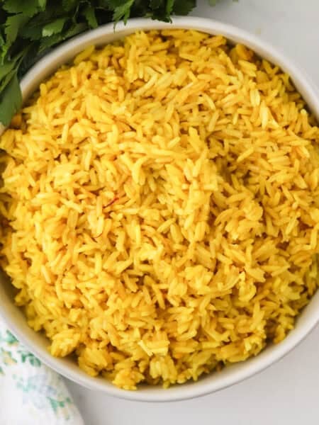 How to make yellow rice, saffron rice recipe. Yellow rice in a white bowl, overhead short.